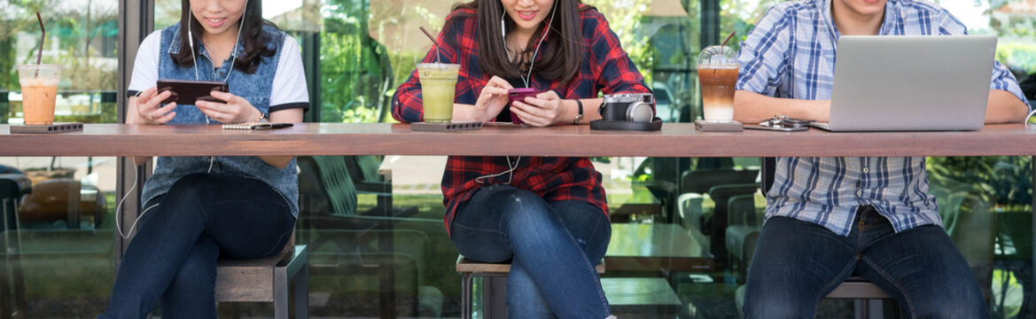 three people using smartphone, tablet, and laptop in coffee shop