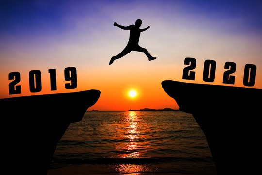 Silhouette young man jumping from 2019 to 2020 years