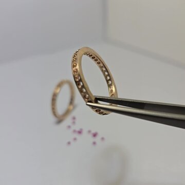 散石如红宝石、祖母绿、蓝宝石等。有一个金戒指置于白色纸张背景上。珠宝店营销照片