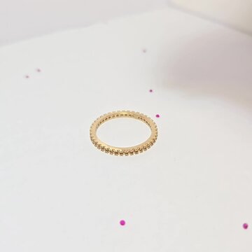 散石如红宝石、祖母绿、蓝宝石等。有一个金戒指镶嵌在白色纸张背景上。珠宝店营销照片