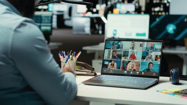 African american worker attending a remote web call at desk using webcam on laptop, interacting with stakeholders after hours. Executive assistant exchanging ideas for networking session. Camera B.