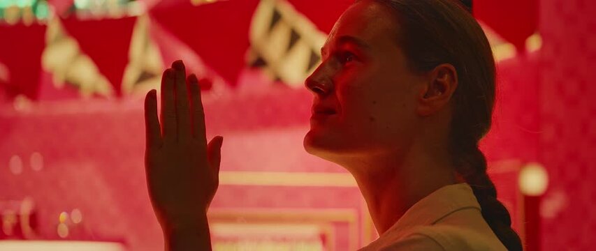 女子将手放在玻璃上，出神地望着明亮橱窗里的奢侈品