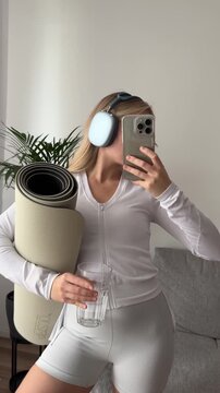 锻炼前手持瑜伽垫和水瓶的女子