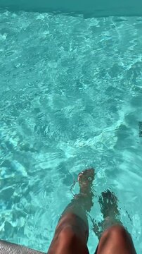 在泛着轻柔涟漪的亮蓝色泳池上方手持冰拿铁。