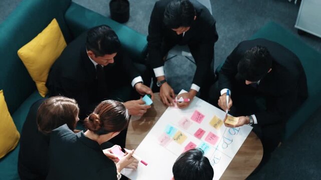 Top view of smart business team write marketing plan and putting stick notes on mind map. Group of happy business people brainstorm financial idea and planning strategy at meeting room. Directorate.