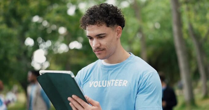 在公园中拿着平板电脑的男子和志愿者为社会责任、非政府组织或慈善活动做规划。借助数字技术思考的男子身处自然环境，为户外社区推广活动制定清单。